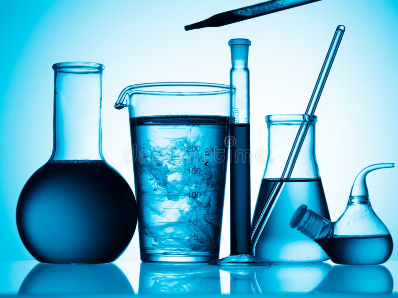 An assortment of flasks, tubes and glass containers filled with liquid shot in blue light. An assortment of flasks, tubes and glass containers filled with liquid shot in blue light.