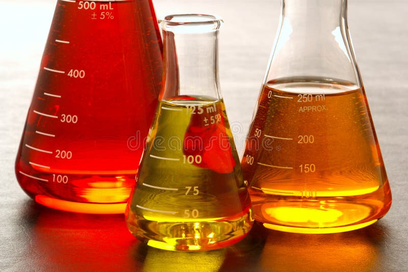 Laboratory glass conical Erlenmeyer flasks filled with red and orange chemical liquid for an experiment in a science research lab. Laboratory glass conical Erlenmeyer flasks filled with red and orange chemical liquid for an experiment in a science research lab