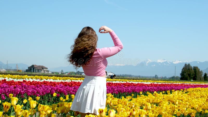 Kolekcja filmów i zdjęć, gdzie dziewczyna w białej spódniczce spaceruje po polu z tulips blue background sky