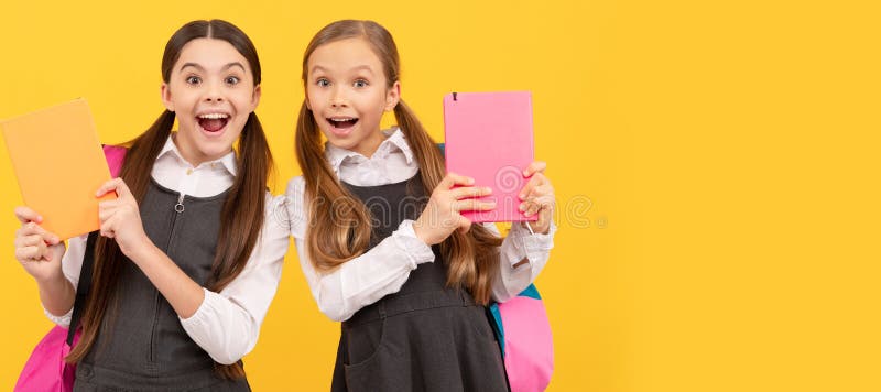 School girls friends. Read me story. Surprised kids hold books yellow background. Childrens literature. Portrait of schoolgirl student, studio banner header. School child face, copyspace. School girls friends. Read me story. Surprised kids hold books yellow background. Childrens literature. Portrait of schoolgirl student, studio banner header. School child face, copyspace