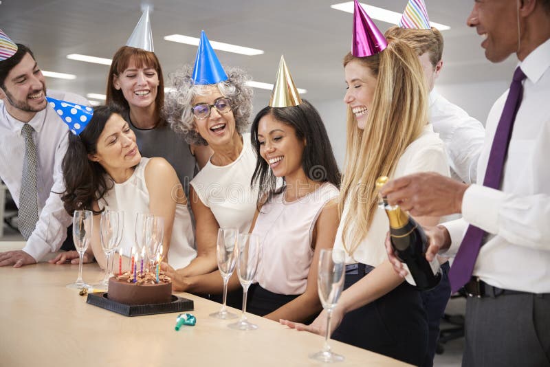 Kollegen, die einen Geburtstag im Büro mit einem Kuchen feiern stockfotografie Kollegen, die einen Geburtstag im Büro mit einem Kuchen feiern stockfotografie