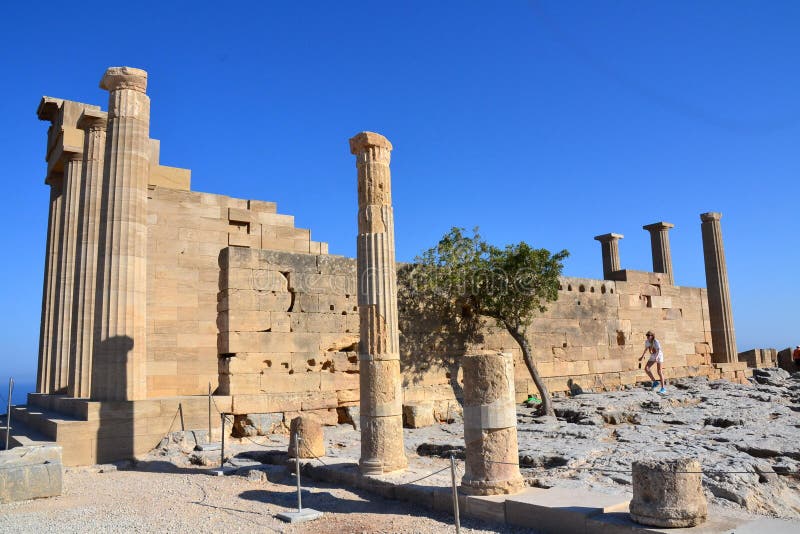 Kolonner på den hellenistic stoaen av akropolen av Lindos, Rhodes, Grekland, blå himmel, olivträdet och den härliga havssikten i royaltyfri foto Kolonner på den hellenistic stoaen av akropolen av Lindos, Rhodes, Grekland, blå himmel, olivträdet och den härliga havssikten i royaltyfri foto