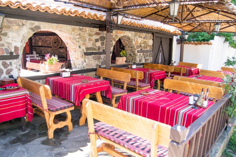 Kolorowi tradycyjni czerwoni tablecloths na drewnianych stołach i ławkach, stara Bułgarska restauracja
