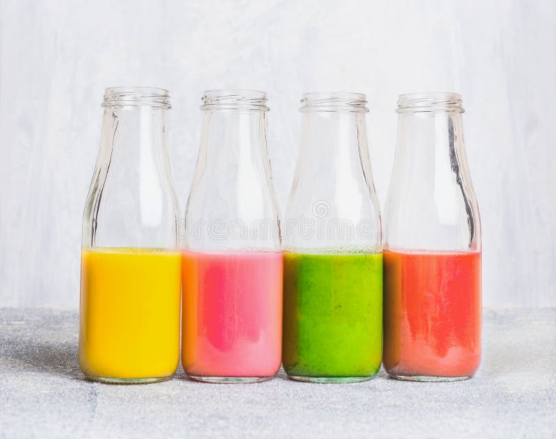 Kolorowy smoothies asortyment w szklanych butelkach na światło stole, boczny widok fotografia stock Kolorowy smoothies asortyment w szklanych butelkach na światło stole, boczny widok fotografia stock