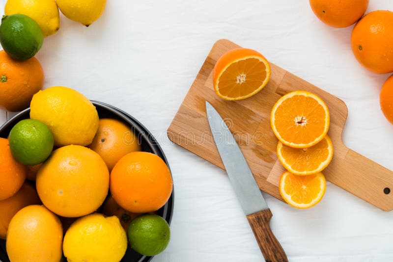 Kom met verschillende types van gehele citrusvruchten: sinaasappelen, grapefruits, kalk en citroenen, en houten raad met plakken royalty-vrije stock foto Kom met verschillende types van gehele citrusvruchten: sinaasappelen, grapefruits, kalk en citroenen, en houten raad met plakken royalty-vrije stock foto