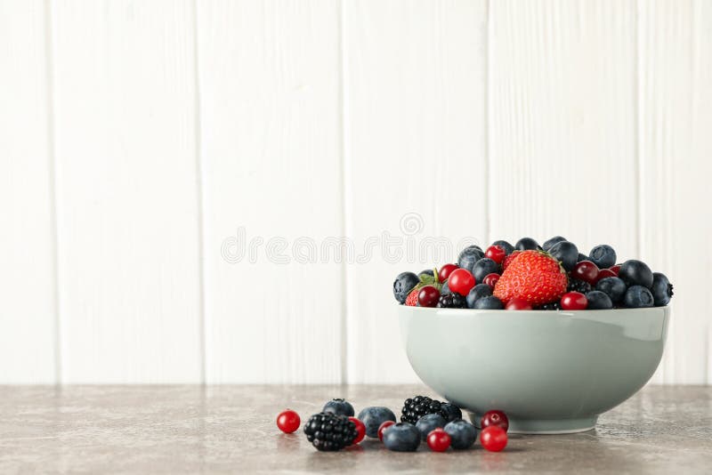 Kom met verse bessen op grijze tabelruimte voor tekst royalty-vrije stock foto's
