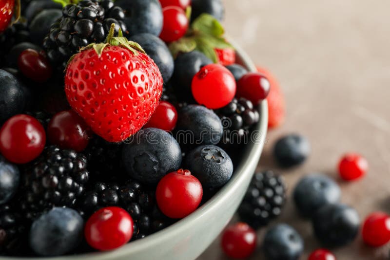 Kom met verse bessen op grijze tafel dicht royalty-vrije stock afbeeldingen