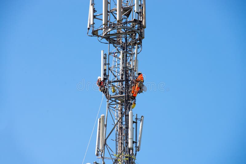 WORCESTER,UK - APRIL 14 2015 : Maintenance workers carry out repairs high up on a communications tower using saftey equipment. WORCESTER,UK - APRIL 14 2015 : Maintenance workers carry out repairs high up on a communications tower using saftey equipment