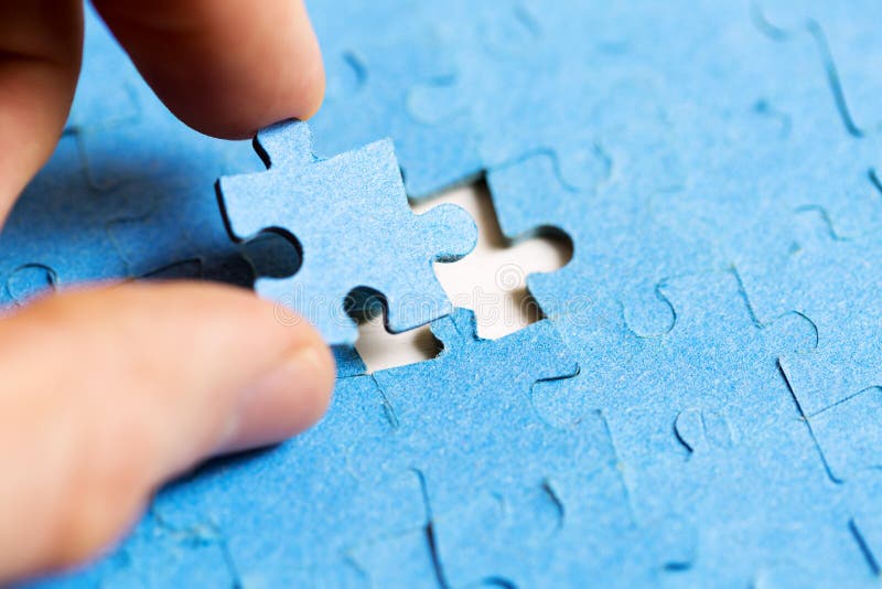 Mission complete concept - hand placing last piece of jigsaw puzzle. Mission complete concept - hand placing last piece of jigsaw puzzle