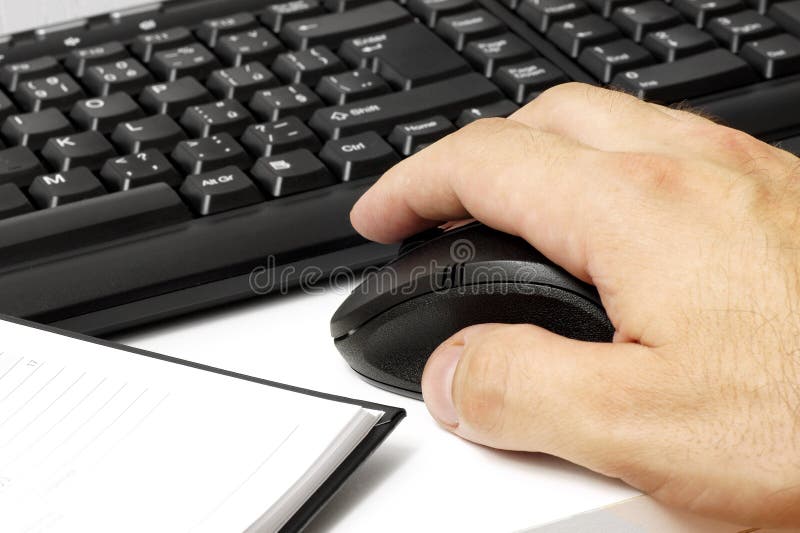 Man's hand holding a computer mouse next to keyboard. Man's hand holding a computer mouse next to keyboard.
