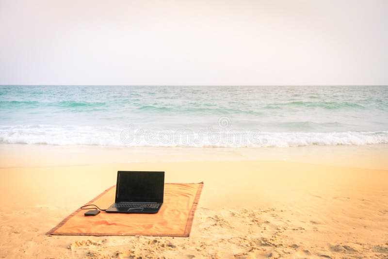 Komputerowy laptop przy plażą na tropikalnym miejscu przeznaczenia