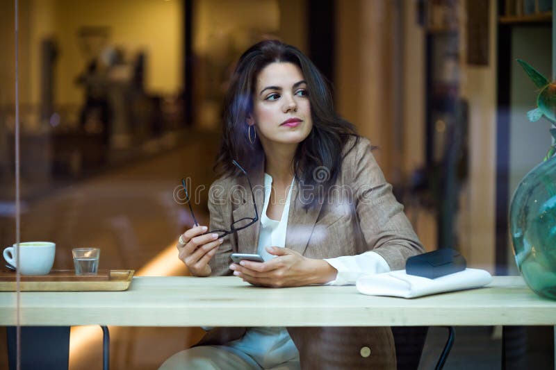 Koncentrerad ung affärskvinna som smsar med hennes mobiltelefon i coffee shop royaltyfri fotografi Koncentrerad ung affärskvinna som smsar med hennes mobiltelefon i coffee shop royaltyfri fotografi