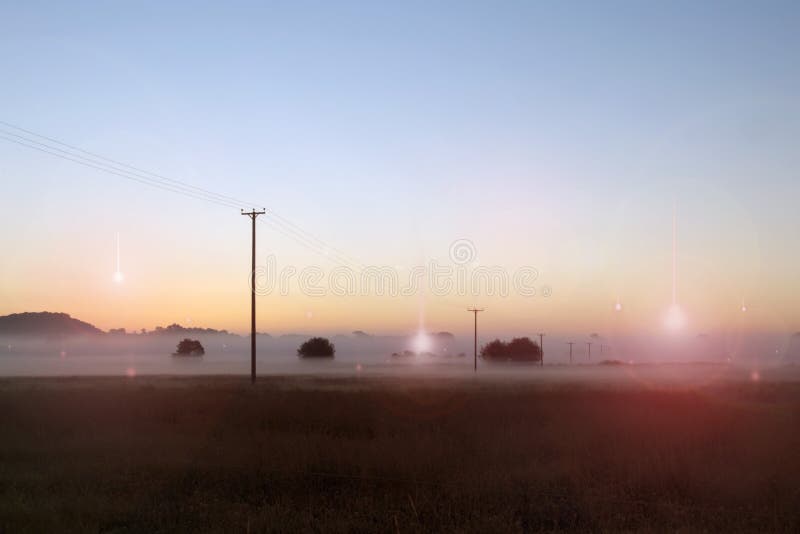 UFO concept of glowing lights falling from the sky, with light flare and light beams. Looking out across a misty field at sunrise. UFO concept of glowing lights falling from the sky, with light flare and light beams. Looking out across a misty field at sunrise.