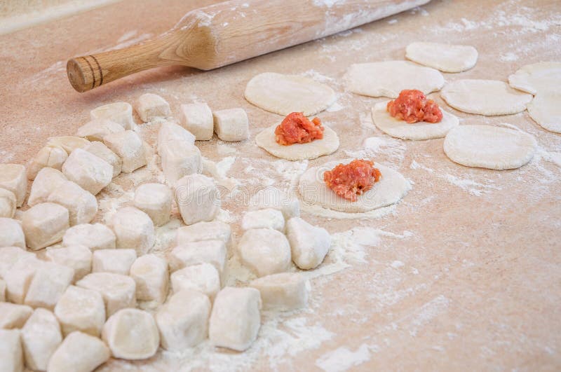 Konceptet med kokkonfektyrer Deg, mjöl, rullstift och malet kött på köksbordet arkivfoton