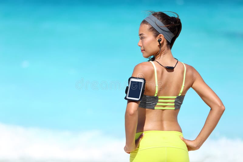 Konditionlöparekvinna med passformen som bär tillbaka telefonarmbindel- och radiohörlurar royaltyfri bild Konditionlöparekvinna med passformen som bär tillbaka telefonarmbindel- och radiohörlurar royaltyfri bild