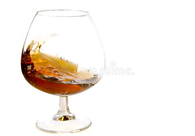 Flowing cognac in glass on white ground. Flowing cognac in glass on white ground