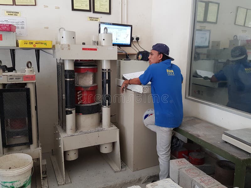 KUALA LUMPUR, MALAYSIA -JUNE 20, 2017: Concrete cube strength compression test at the laboratory using compression machine. Skilled laboratory staff handling recording the result. KUALA LUMPUR, MALAYSIA -JUNE 20, 2017: Concrete cube strength compression test at the laboratory using compression machine. Skilled laboratory staff handling recording the result.