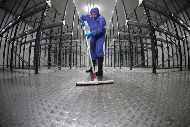 Konstanter Reinigungsfußboden der Arbeitskraft im Lagerhaus lizenzfreie stockbilder Konstanter Reinigungsfußboden der Arbeitskraft im Lagerhaus lizenzfreie stockbilder