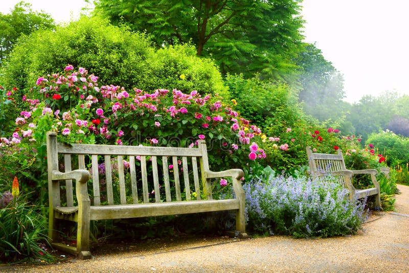 Konstbänken och blommor i morgonen i ett engelska parkerar arkivfoton Konstbänken och blommor i morgonen i ett engelska parkerar arkivfoton