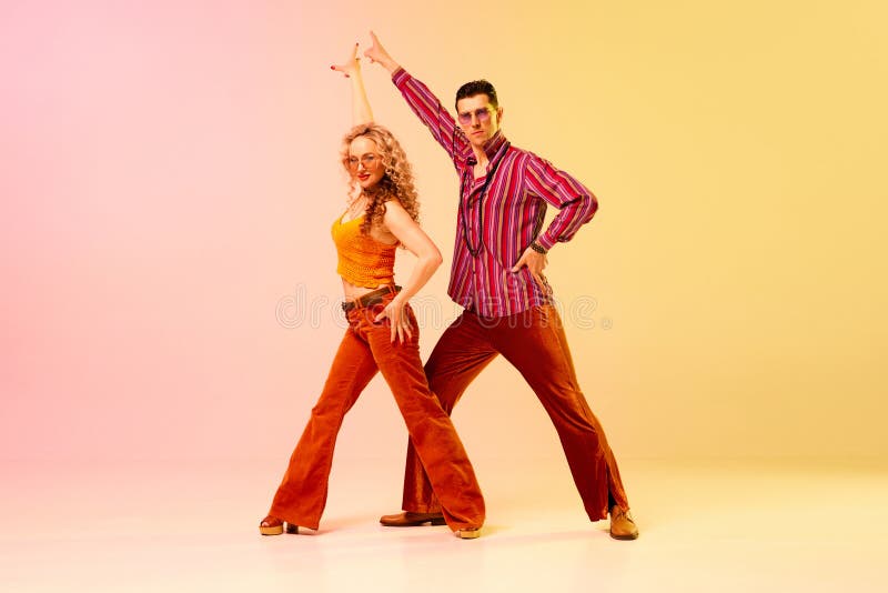 Konstnärlig, uttrycksfull man och kvinna i snygga kläder som dansar diskoretro mot gradient rosa gul bakgrund. Koncept för modedans modekonst hobby-musik 70:s hobby.