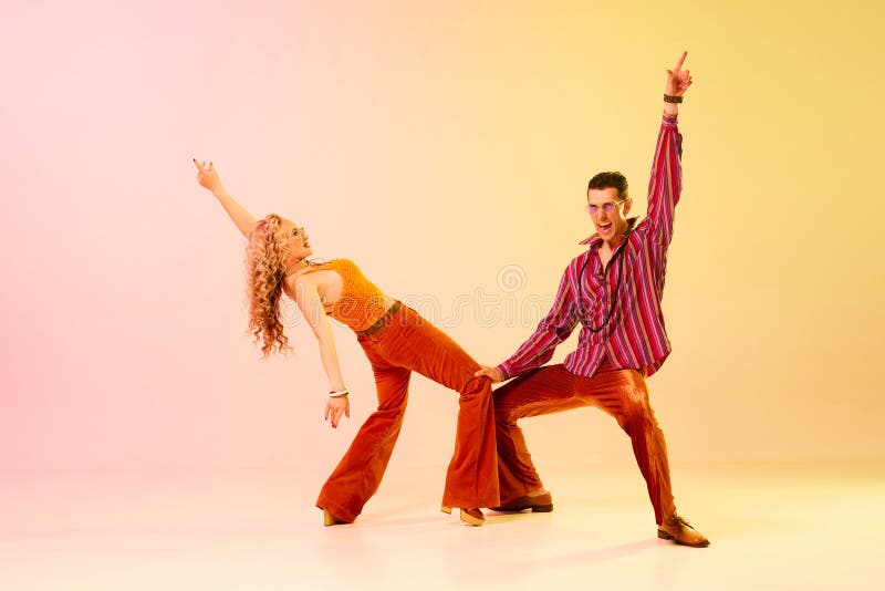 Konstnärligt uttryckligt par man och kvinna som emotionellt dansar discodans mot gradient rosa gul bakgrund arkivfoto