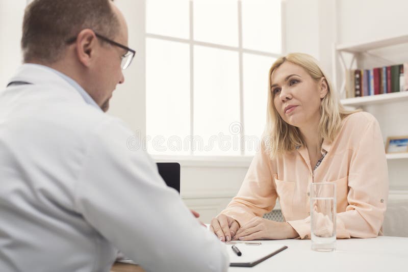 Konsulterande kvinna för allvarlig doktor i sjukhus arkivbild Konsulterande kvinna för allvarlig doktor i sjukhus arkivbild