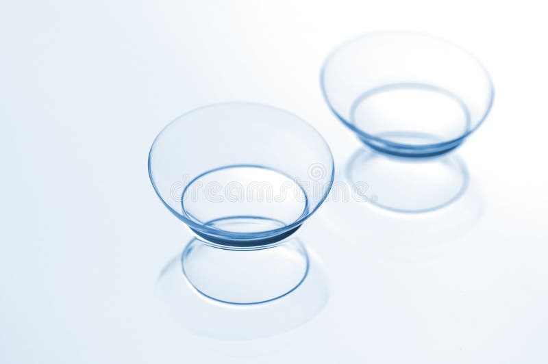 Two contact lenses with reflections on a blue background. Two contact lenses with reflections on a blue background.