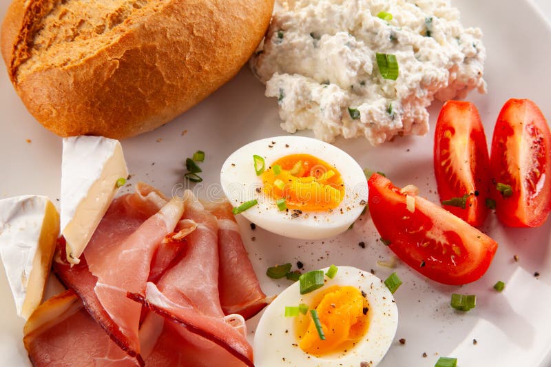 Kontinentales Frühstück gekochte Eier, Tomaten aus weißem Käse und Brötchen auf weißem Hintergrund lizenzfreie stockfotografie