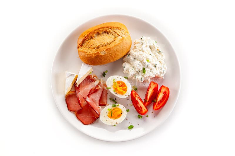 Kontinentales Frühstück gekochte Eier, Tomaten aus weißem Käse und Brötchen auf weißem Hintergrund stockfotografie