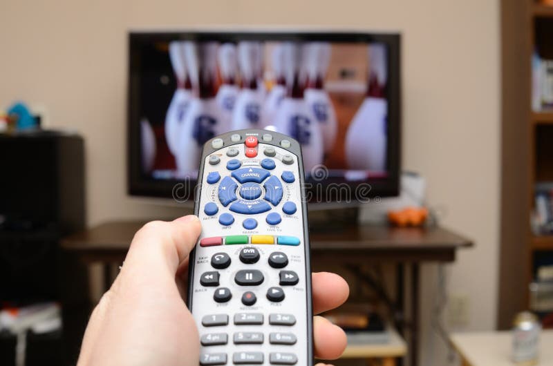 Television remote in the foreground with selective focus and television in the background. Television remote in the foreground with selective focus and television in the background.