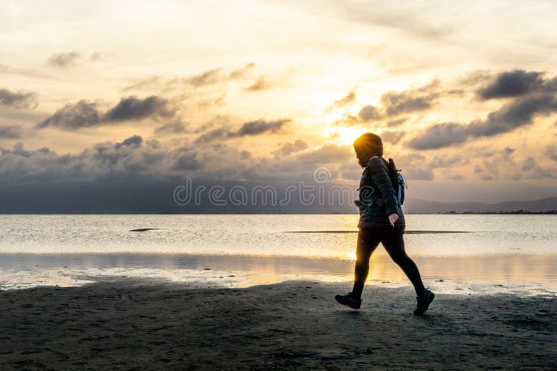 Kontur av en oigenkännlig kvinna som går på stranden på solnedgången royaltyfri fotografi Kontur av en oigenkännlig kvinna som går på stranden på solnedgången royaltyfri fotografi