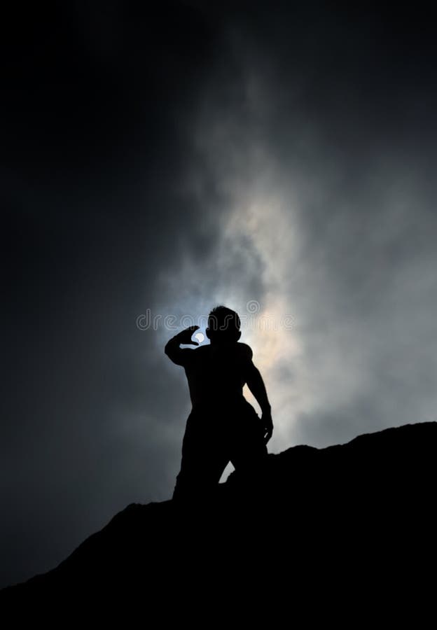Kontur av mannen som står på Rock som upp till når himlen under partisk förmörkelse