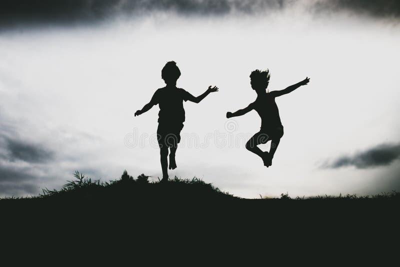 Silhouettes of kids jumping from a sand cliff at the beach. Active healthy kids enjoying their time at the beach. Fraternal twins playing together. Friends having fun during summer vacation. Nice day at the lake. Silhouettes of kids jumping from a sand cliff at the beach. Active healthy kids enjoying their time at the beach. Fraternal twins playing together. Friends having fun during summer vacation. Nice day at the lake.