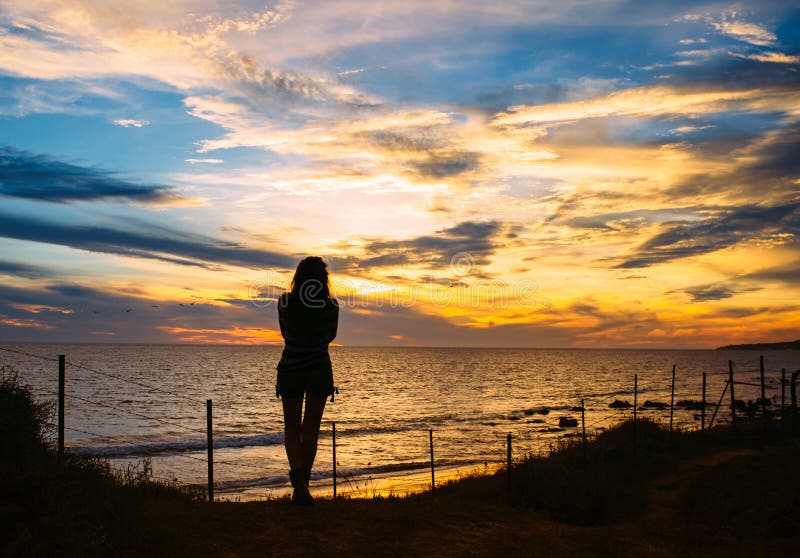 Konturn av kvinnan står på stranden på solnedgång royaltyfri fotografi Konturn av kvinnan står på stranden på solnedgång royaltyfri fotografi
