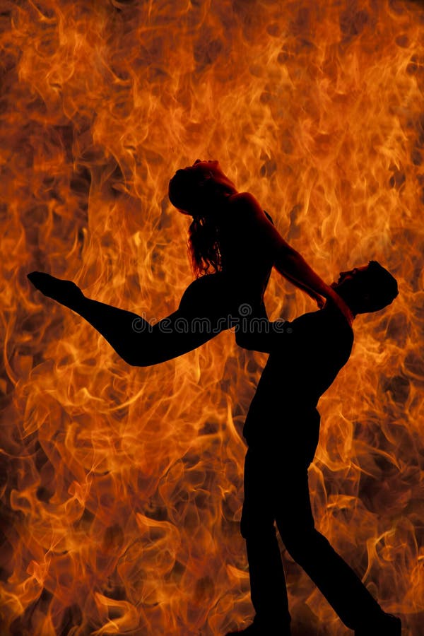 A silhouette of a men and women dancing, he is doing a lift, with a background of fire. A silhouette of a men and women dancing, he is doing a lift, with a background of fire.