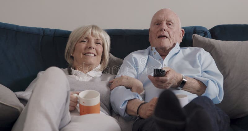 Konversationstv och ett lyckligt gammalt par slappna av i bonusen eller njut av TV-filmer eller prenumerationsvideo arkivfilmer
