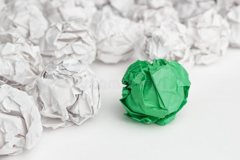 Overhead shot of crumpled paper in oder and green one standing out. great idea concept on the white office table. Overhead shot of crumpled paper in oder and green one standing out. great idea concept on the white office table