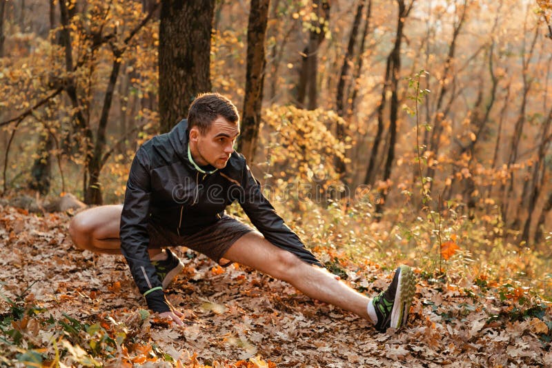 Konzept des Sports und des aktiven Lebensstils Ein junger Mann engagiert sich in Warm-up, Fitness im Herbstwald lizenzfreie stockfotos Konzept des Sports und des aktiven Lebensstils Ein junger Mann engagiert sich in Warm-up, Fitness im Herbstwald lizenzfreie stockfotos