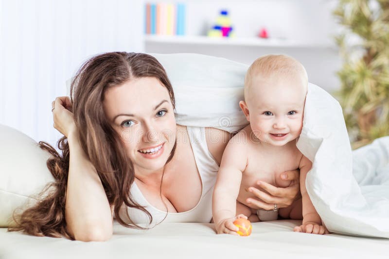 Konzept von glücklichen Müttern: glückliche Mutter und ihr jähriges Kind, die auf dem Sofa im Schlafzimmer spielt stockbild Konzept von glücklichen Müttern: glückliche Mutter und ihr jähriges Kind, die auf dem Sofa im Schlafzimmer spielt stockbild