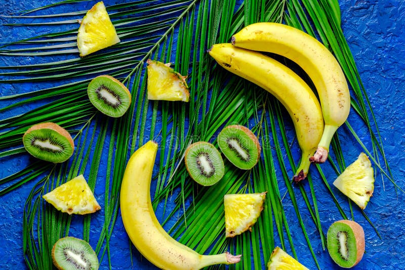 Konzept von tropischen Früchten des Sommers Banane, Kiwi, Ananas und Palme verzweigen sich auf Draufsicht des blauen Tabellenhint stockbilder Konzept von tropischen Früchten des Sommers Banane, Kiwi, Ananas und Palme verzweigen sich auf Draufsicht des blauen Tabellenhint stockbilder