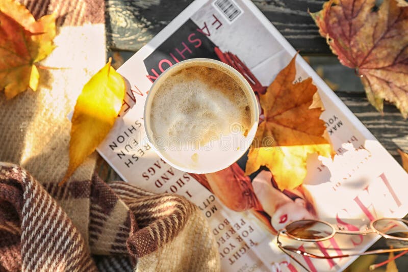 Kop van hete koffie met tijdschrift en de herfstbladeren op houten bank stock foto Kop van hete koffie met tijdschrift en de herfstbladeren op houten bank stock foto