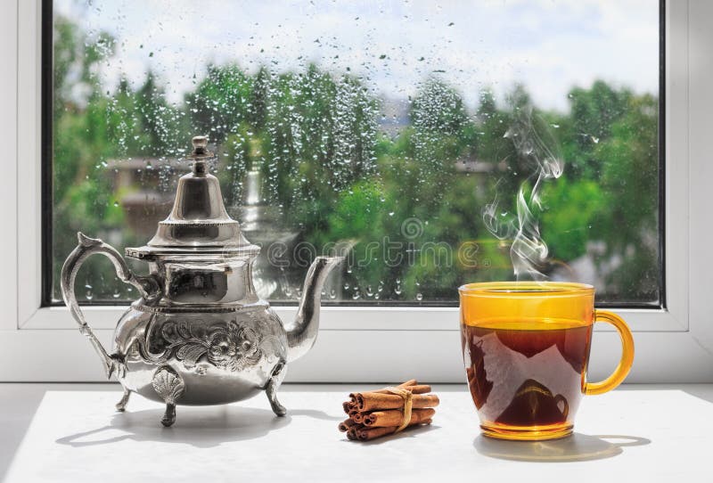 Kop van hete koffie op de vensterbank Regendalingen op het glas Regenachtig weer achter het venster