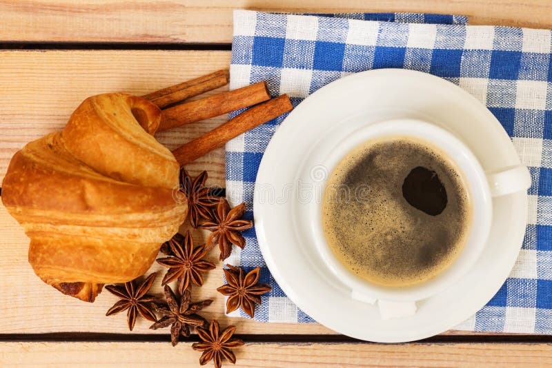 Kop van koffie en een croissantbroodje op een houten achtergrond stock fotografie Kop van koffie en een croissantbroodje op een houten achtergrond stock fotografie
