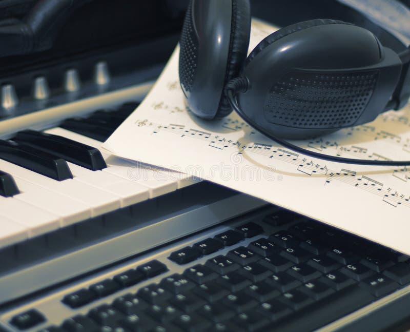 Headphones and music sheet on synthesizer keyboard and computor keyboard,musician equipment. Headphones and music sheet on synthesizer keyboard and computor keyboard,musician equipment