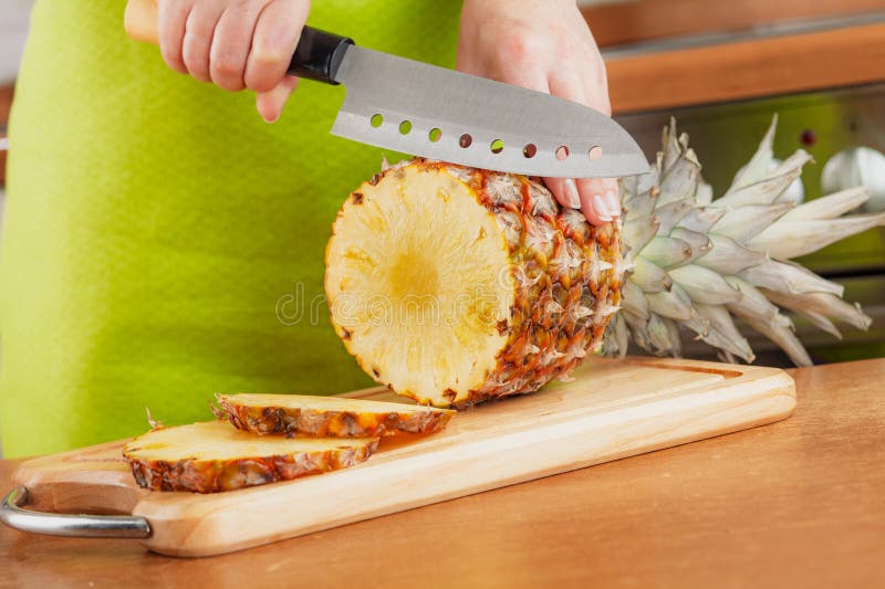 Kopning av färsk ananas på styckningsskivan arkivbilder