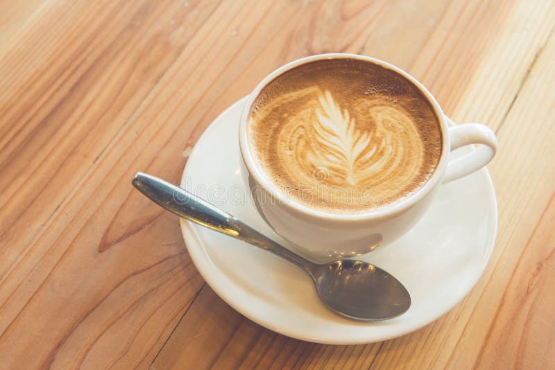 Kopp av lattekonst på den wood tabellen arkivfoto