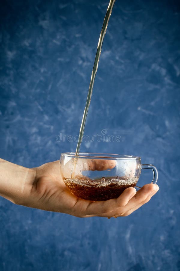 Kopp för hand för kvinna` s hållande glass med hällande te royaltyfria bilder Kopp för hand för kvinna` s hållande glass med hällande te royaltyfria bilder