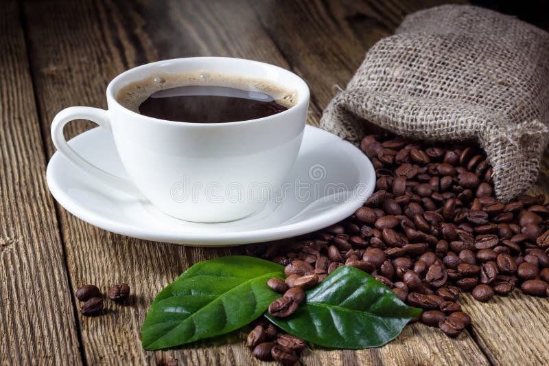 Kopp kaffe, bönor och blad arkivfoto