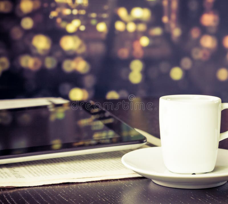 Kopp kaffe framme av den digitala minnestavlaPC:n nära fönster, tappningstil royaltyfria bilder Kopp kaffe framme av den digitala minnestavlaPC:n nära fönster, tappningstil royaltyfria bilder