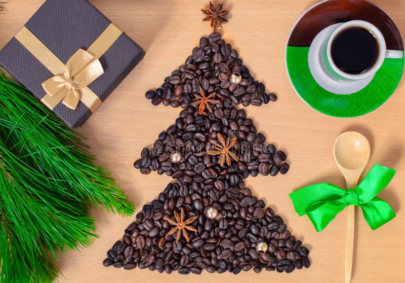 Kopp kaffe med julgåvor och garneringar Shape av julträdet som göras av kaffebönor på trätabellen arkivbild Kopp kaffe med julgåvor och garneringar Shape av julträdet som göras av kaffebönor på trätabellen arkivbild